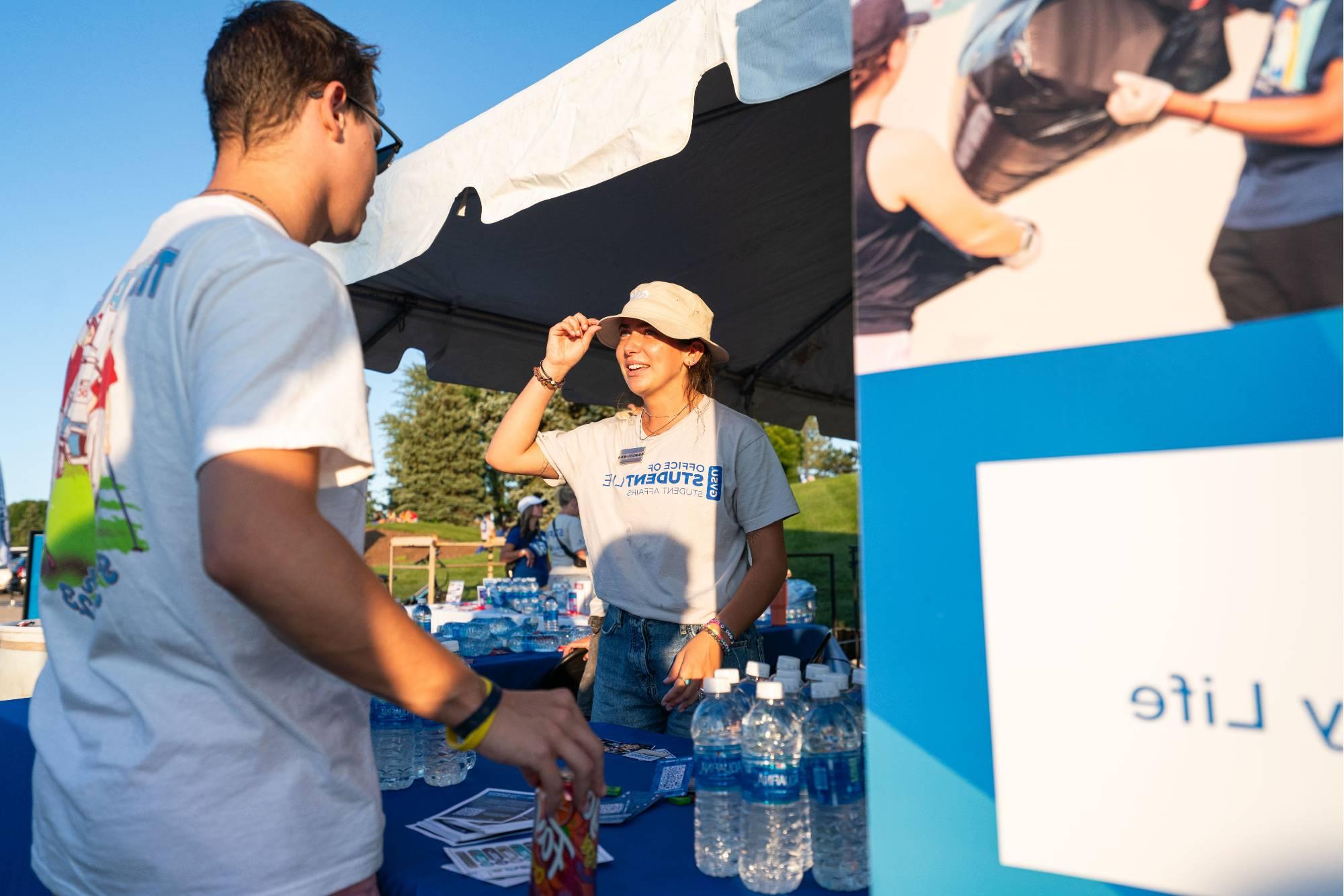 Student worker welcomes student to the event and hands them a water bottle